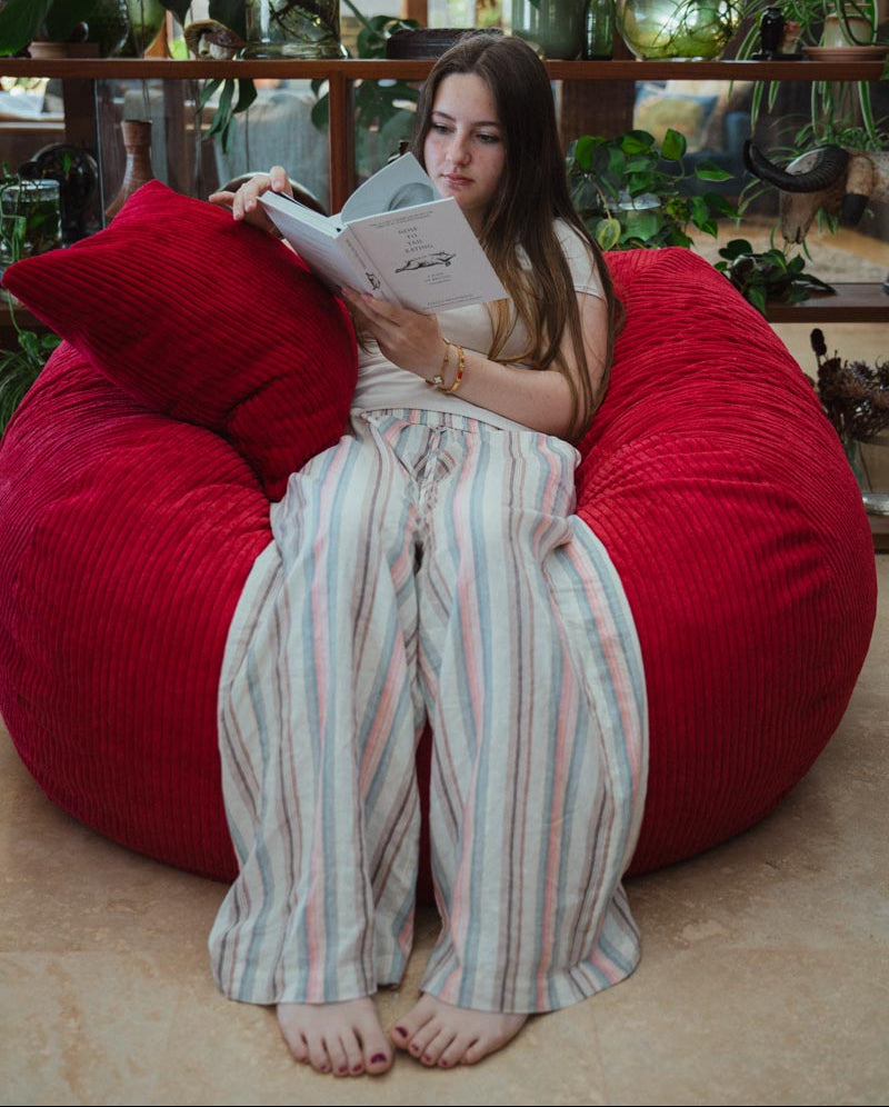 Person reading a book on a red bean bag chair in a casual setting
