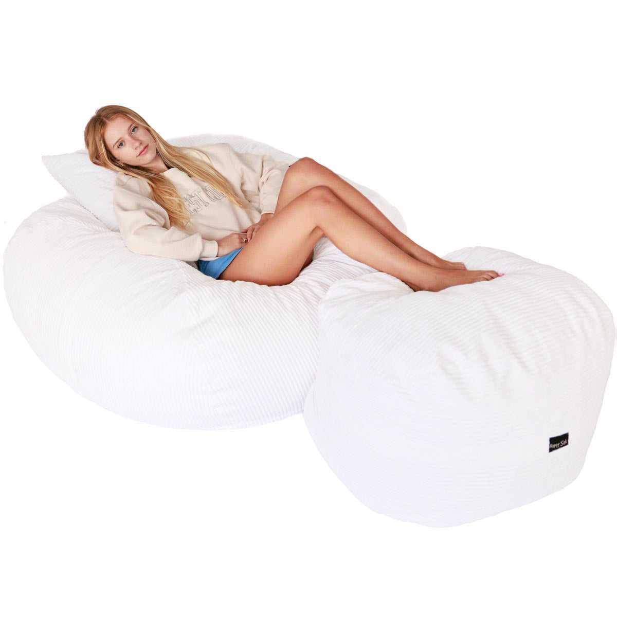 Woman lying on a large white bean bag chair against a white background