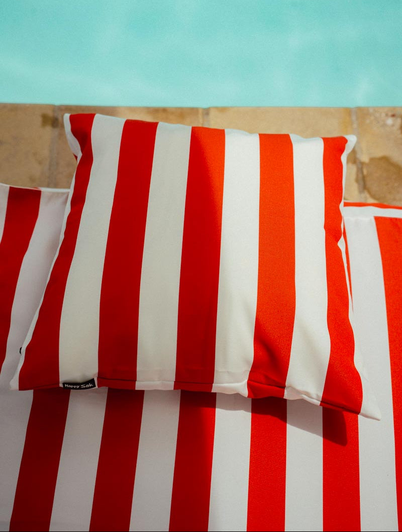Red and white striped pillow on a wooden surface with a light blue background