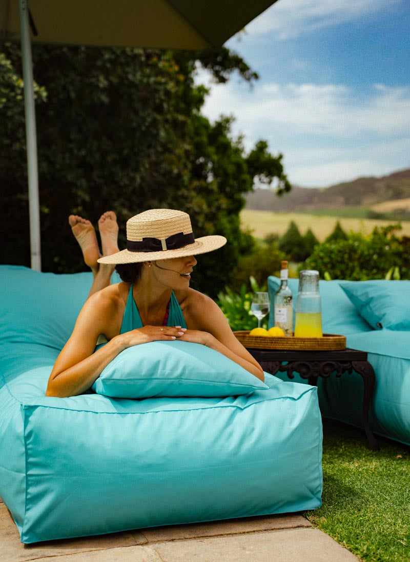 Woman relaxing on a turquoise bean bag chair with a scenic background