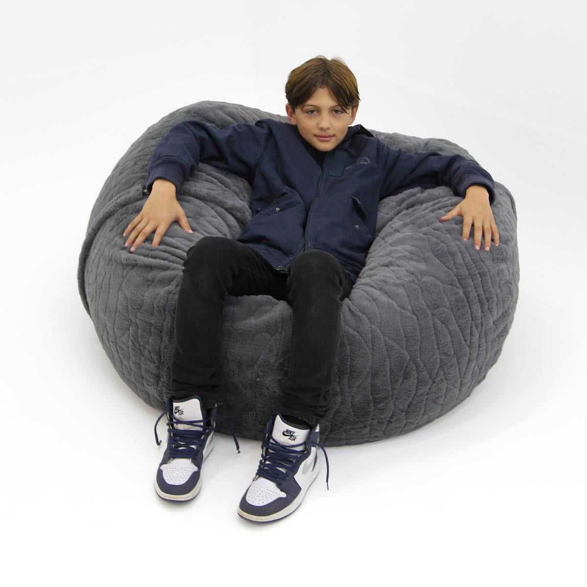 Person sitting on a large gray bean bag chair against a white background
