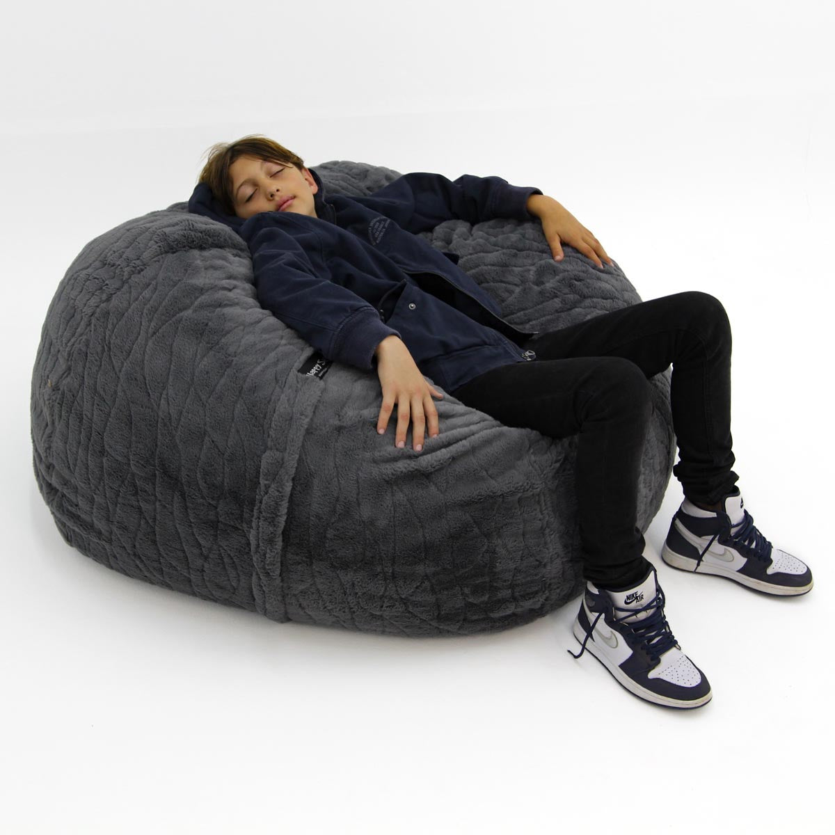 Person sitting on a large gray bean bag chair against a white background
